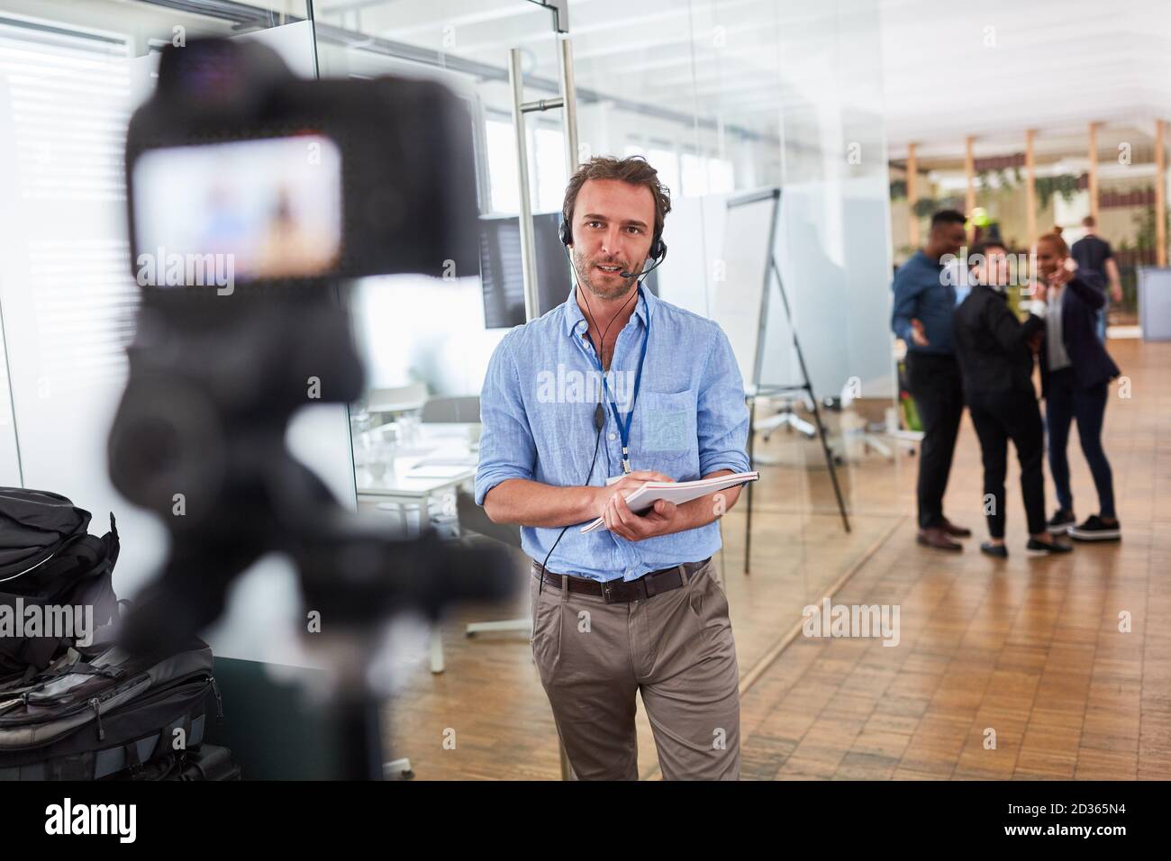 Uomo d'affari come reporter o allenatore di fronte al videocamera per un'intervista Foto Stock