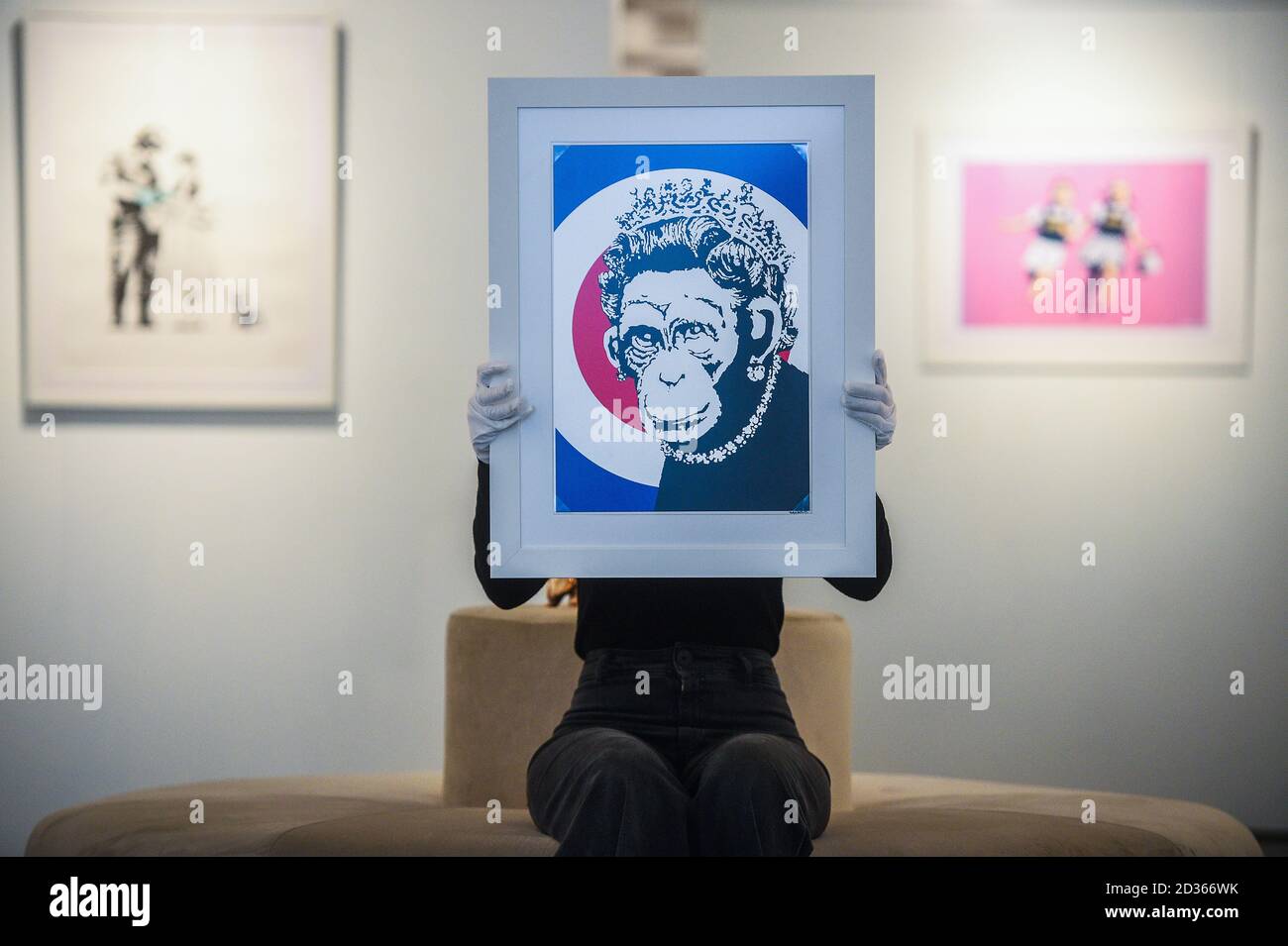 L'assistente alla Galleria Sophia Shim conserva una stampa in edizione limitata di Monkey Queen (2003) di Banksy, parte della mostra 'Catch Me If You Can', presso la HOFA Gallery di Mayfair, Londra. Foto Stock