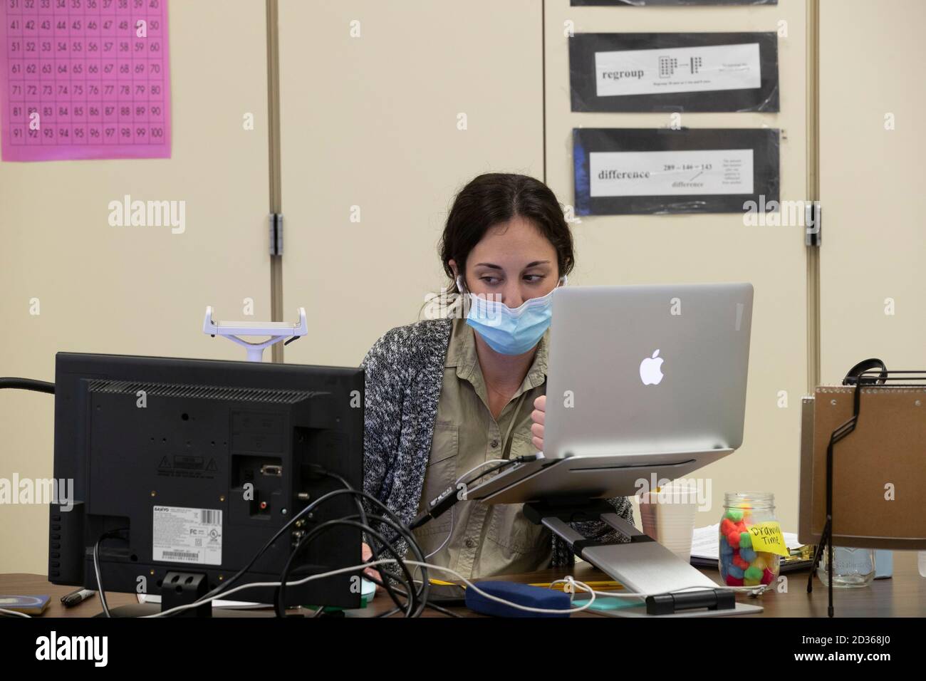 Austin, TX USA 6 ottobre 2020: L'assistente di insegnamento utilizza due computer per tenere gli studenti online durante una sessione di classe ibrida presso Campbell Elementary. Alcuni studenti sono tornati in classe per la prima volta da quando il coronavirus ha chiuso le scuole a marzo, mentre altri hanno continuato a imparare a distanza dalle loro case. Credit: Bob Daemmrich/Alamy Live News Foto Stock