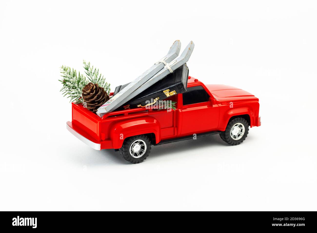 Concetto di vacanza invernale. Giocattolo rosso trendy con sci, valigia, ramo in abete e cono in abete nel tronco. Parte del set Foto Stock