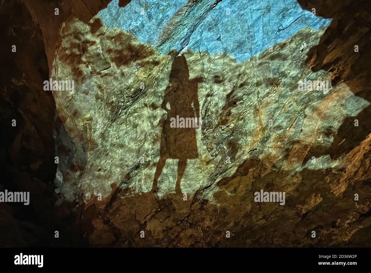 L'ombra di una ragazza sulla parete di una grotta con i riflessi della superficie d'acqua del sotterraneo Saint-Leonard in Svizzera. Foto Stock