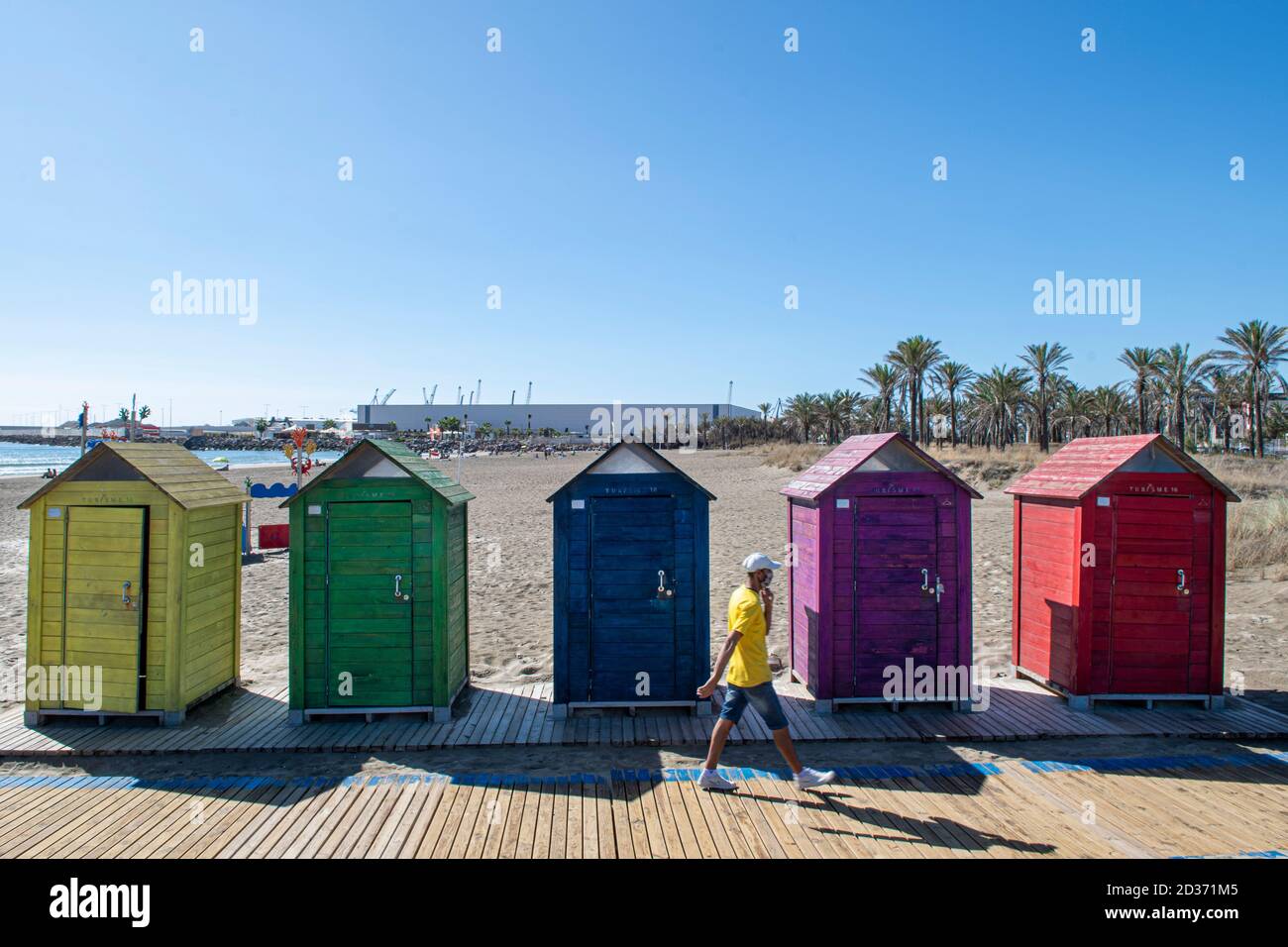 Colorate cabine per il bagno con passanti che le passano davanti. Foto Stock