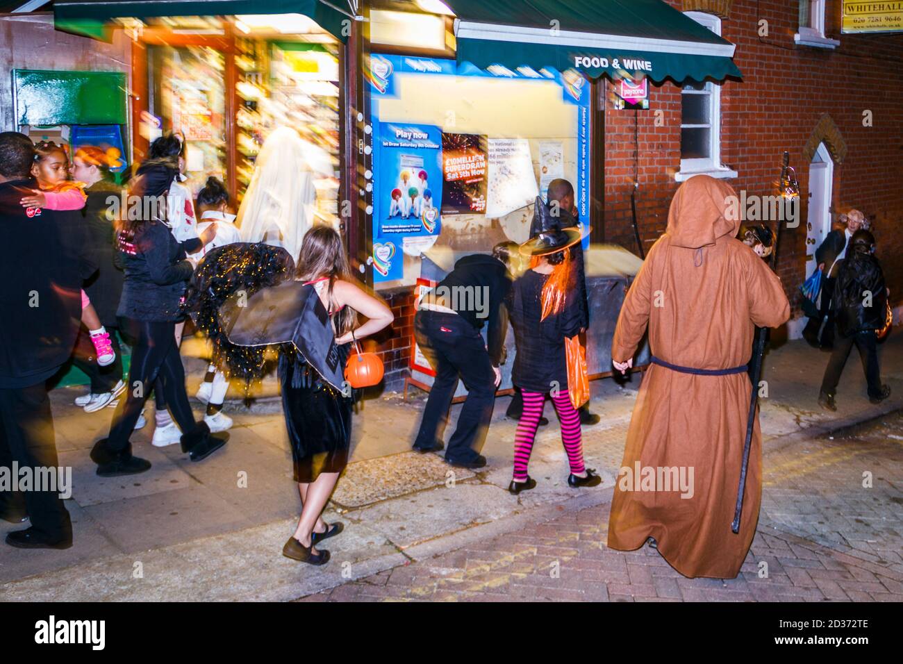 Trick-or-treaters nei costumi di Halloween, guidati dal 'Grim Reaper' che vagano per le strade alla ricerca di dolci e altre ricompense, Londra, Regno Unito Foto Stock