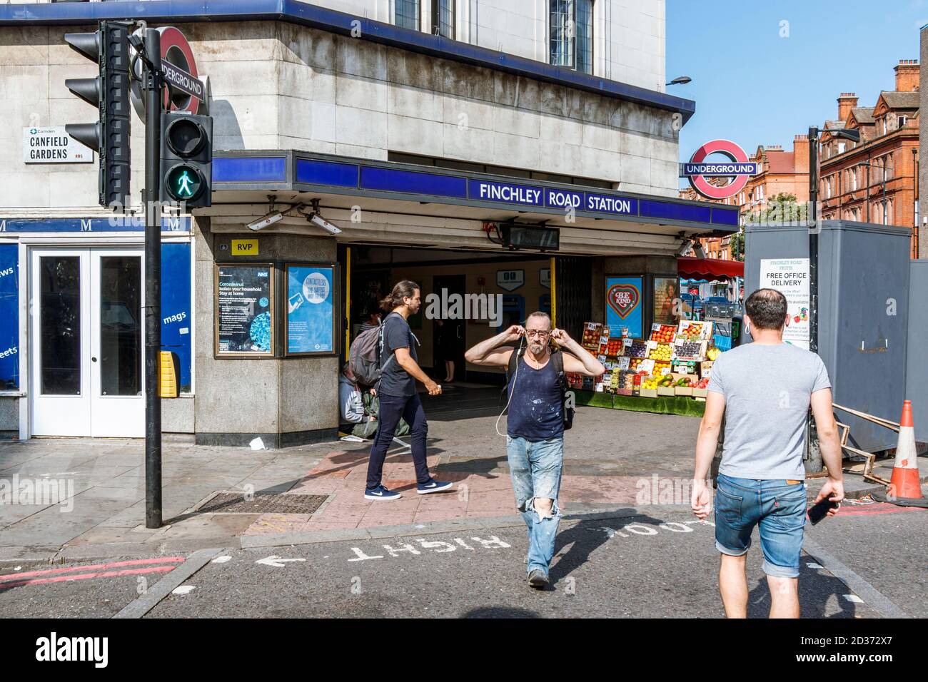 Pedoni che attraversano la strada fuori dalla stazione della metropolitana di Finchley Road su un insolitamente caldo tardo pomeriggio di settembre, Londra, Regno Unito Foto Stock