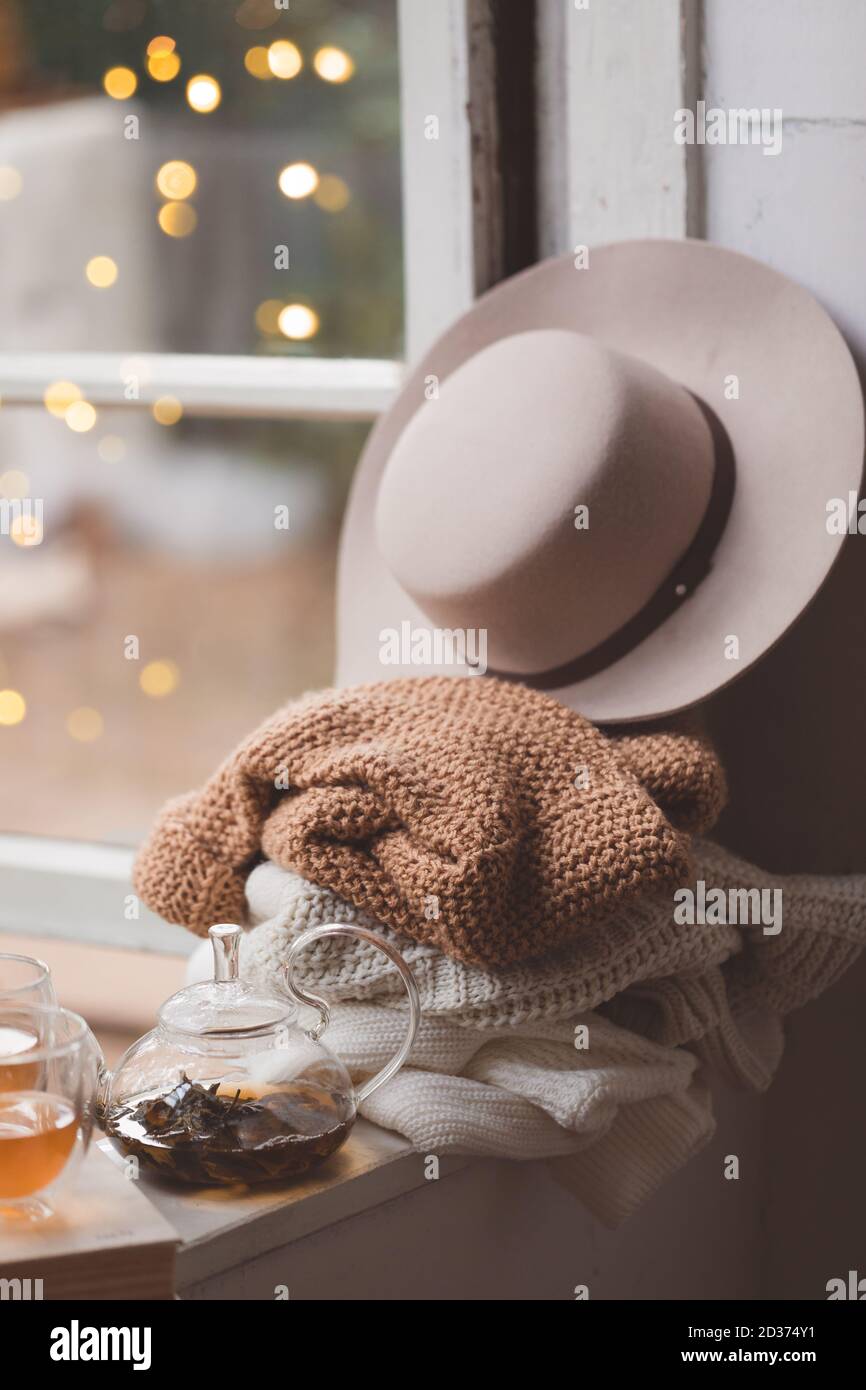 Calda e accogliente Hygge con pullover bianchi e beige e un cappello a davanzale, tonato Foto Stock