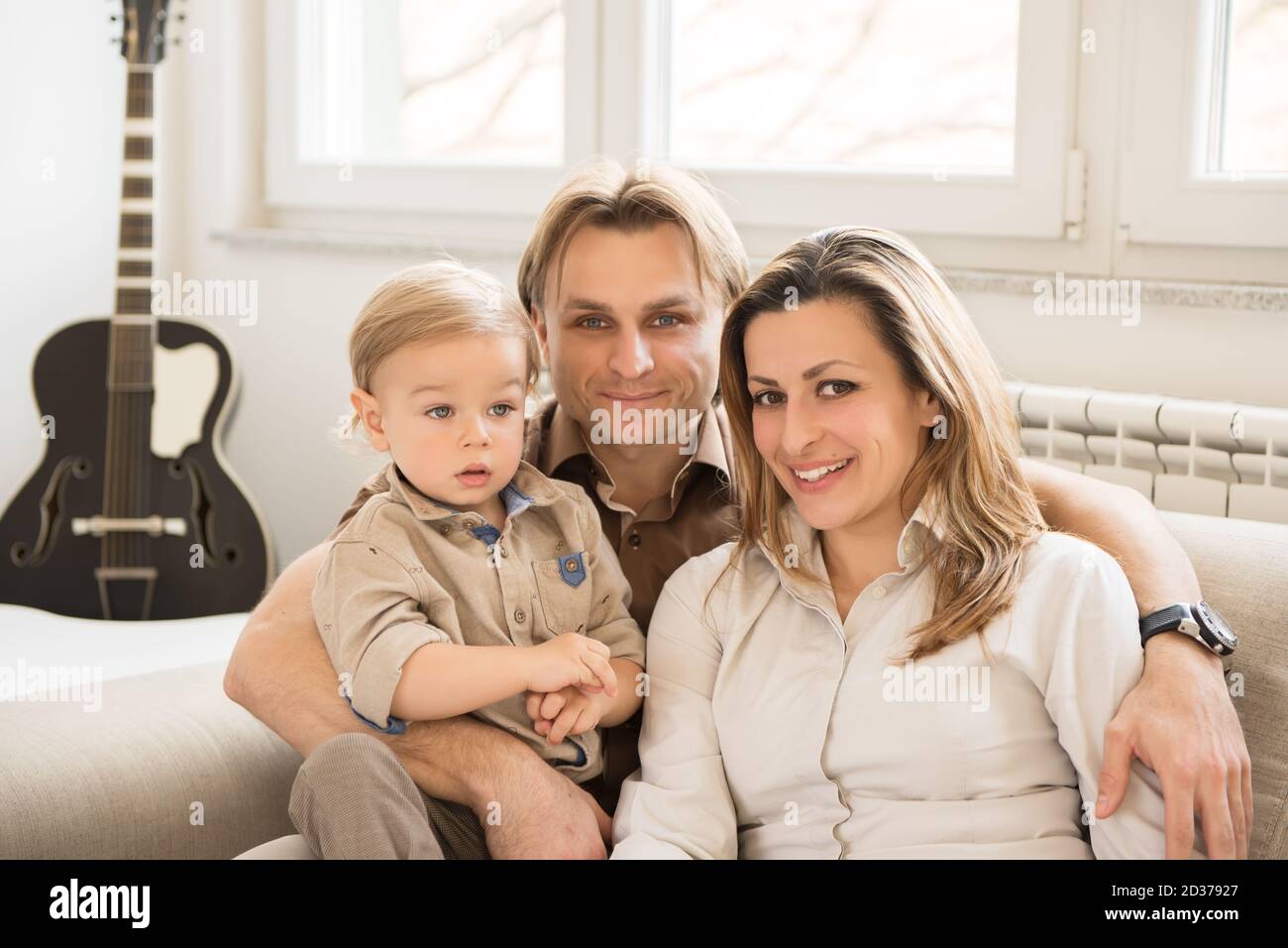 Ritratto dei genitori felici seduti sul divano con il loro bel bambino. Valori familiari. Foto Stock