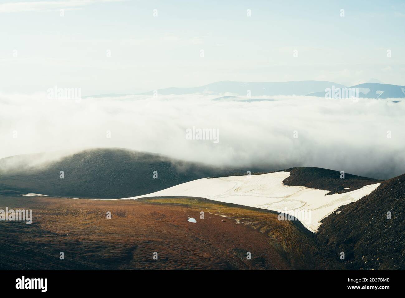 Suggestivo paesaggio alpino con la nuvola bassa gigante sopra la montagna rocciosa con ghiacciaio. Grande e densa nuvola sopra la valle dell'altopiano. Splendido paesaggio in alto Foto Stock