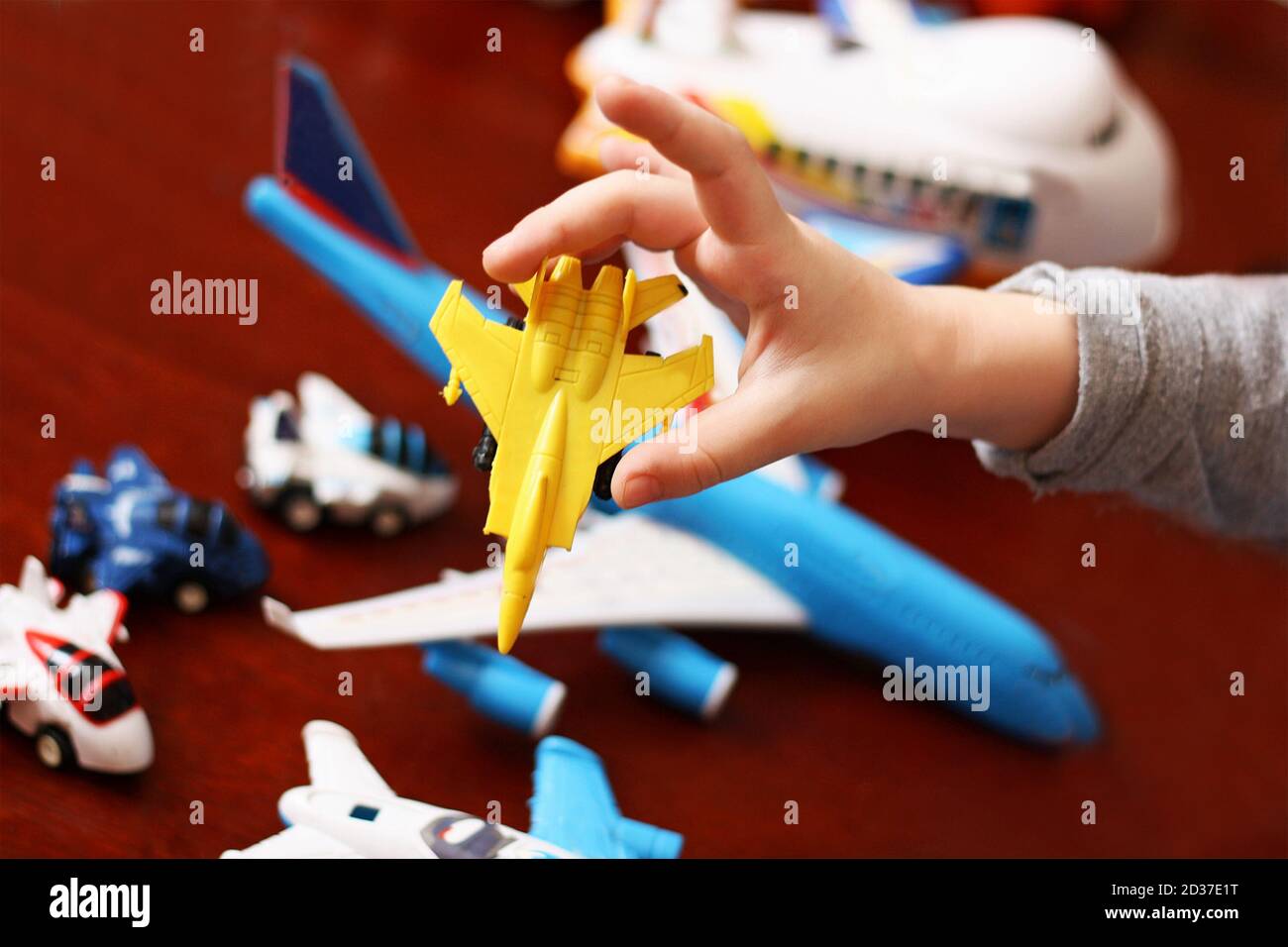Parte dell'immagine di un bambino che gioca con una collezione di aerei di plastica giocattolo. Foto Stock