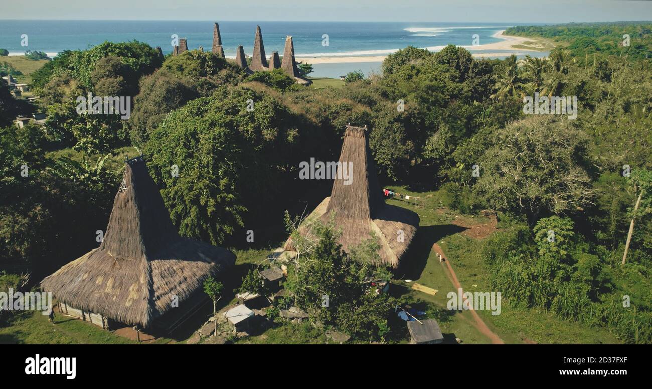 Vista aerea dei tetti unici dell'Indonesia sulla costa di sabbia della baia dell'oceano e del verde paesaggio tropicale della giungla. Varietà naturale di verde valle campagna e paradiso spiaggia di sabbia di Sumba Island, Asia Foto Stock