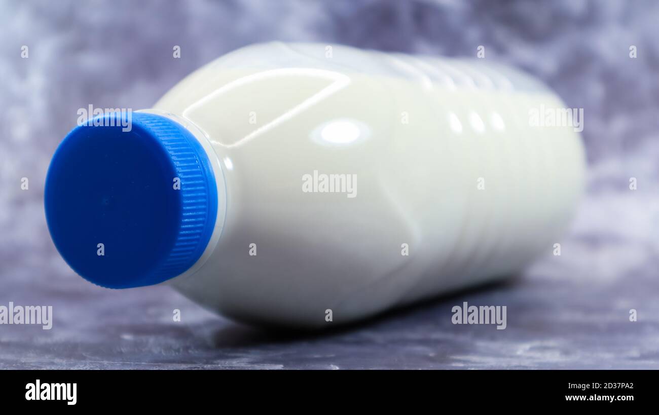 Una bottiglia di plastica con un tappo blu di latte fresco regolare su  fondo di marmo