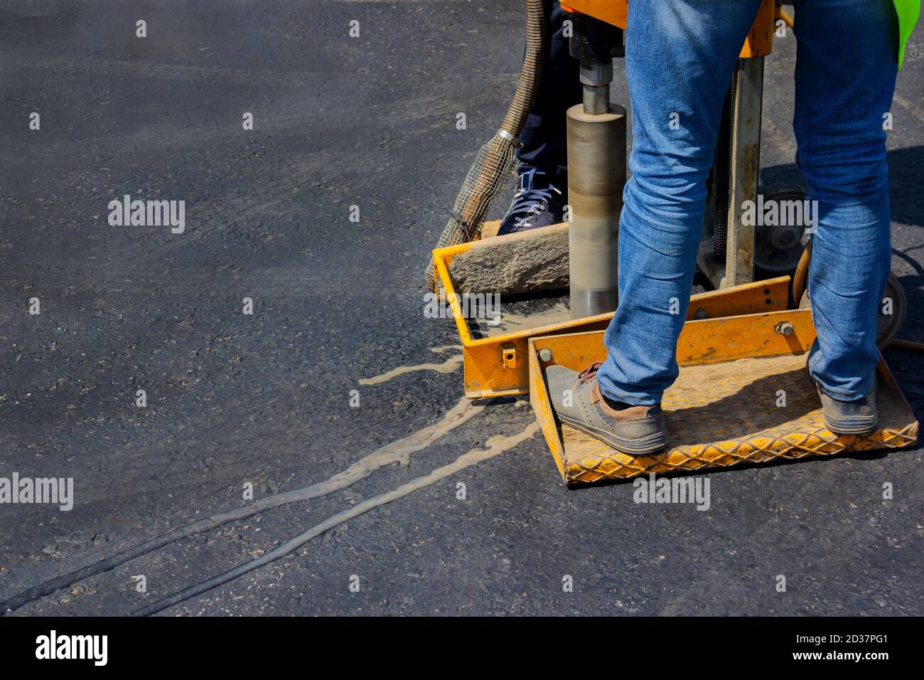 Il costruttore con macchina troncatrice sta perforando nuovo asfalto per controllarlo. Foto Stock