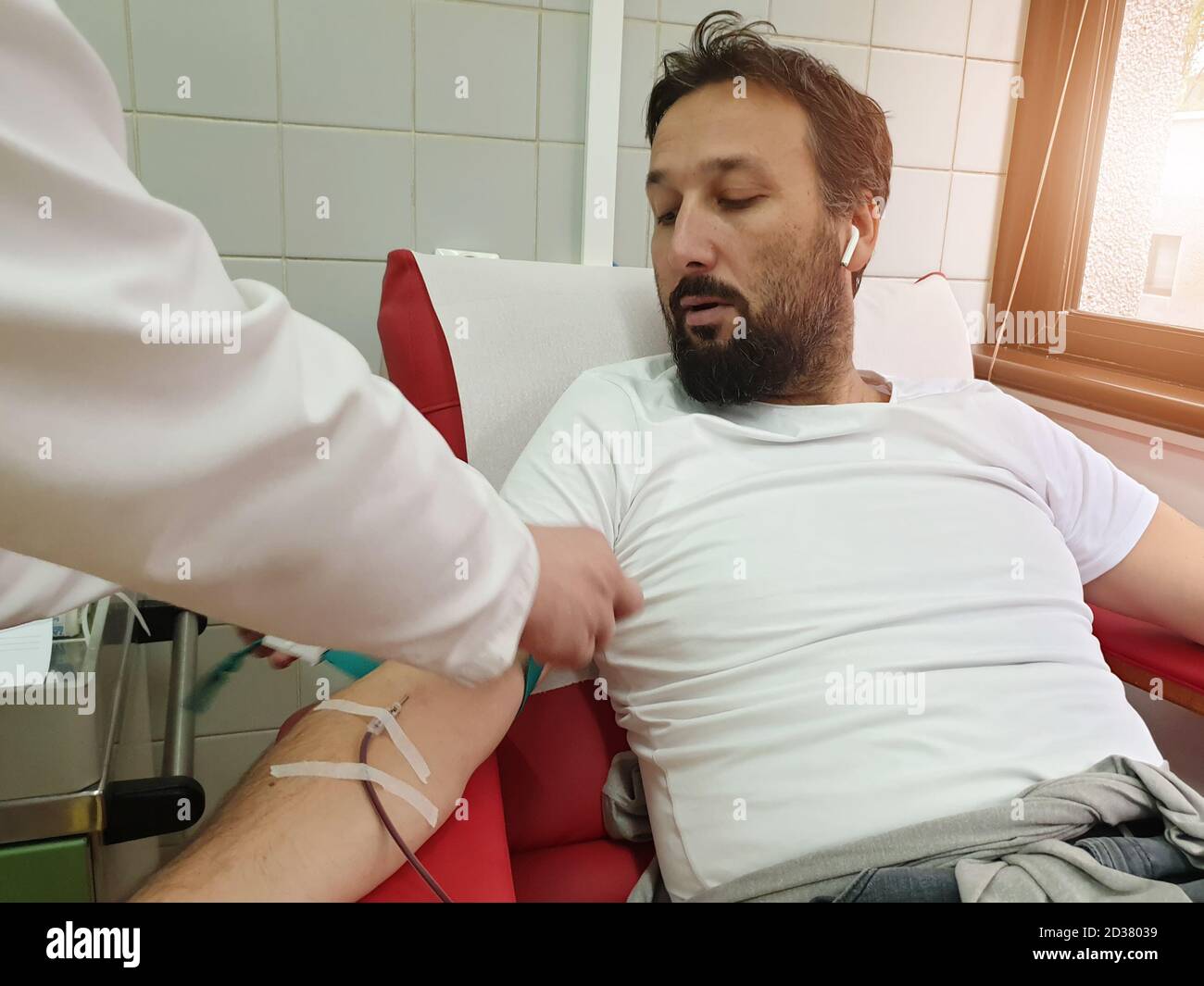 Donatore di sangue seduto in sedia medica mentre dà il sangue. Concetto di donazione di sangue. Concetto che salva una vita Foto Stock