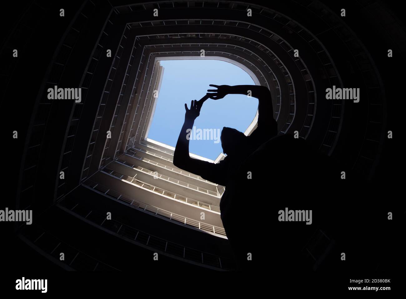 Il fotografo scatta la foto su un imponente edificio moderno sullo sfondo. Silhouette di un uomo che tiene il telefono cellulare per scattare una foto. Turistico in città Foto Stock