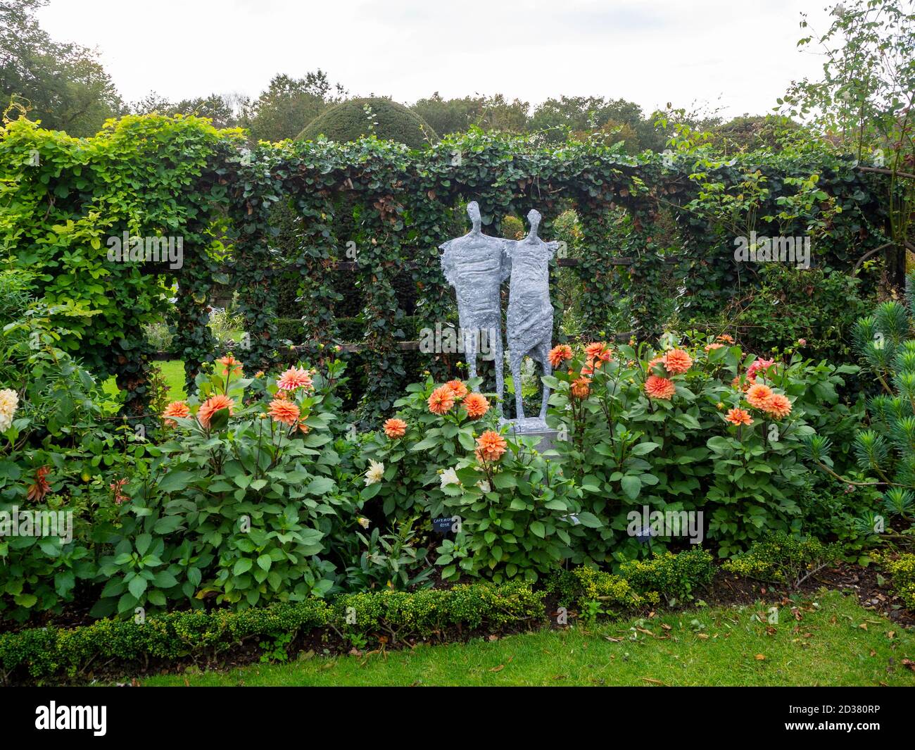 Chenies Manor giardini nel mese di settembre. Lo sculpuro di Victoria Atkinson, 'Halcyon' tra i Dahlia 'Nicolas' con un avy e Akebia clad trellis. Foto Stock