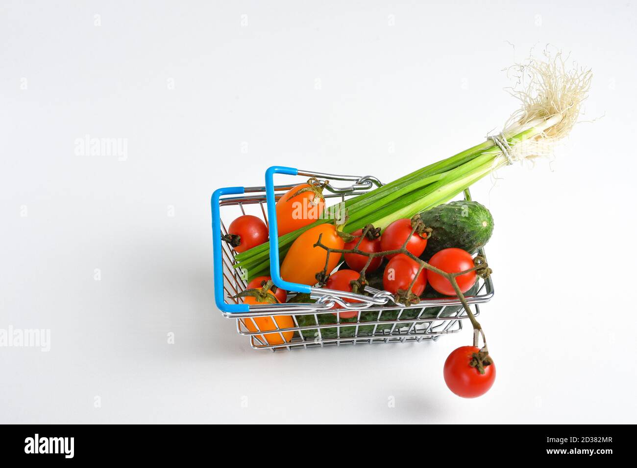 Verdure in un cesti di vimini basket.Shopping cart di alimentari metallo su sfondo bianco. Concetto di cestino alimentare. Primo piano. Disposizione piatta. Messa a fuoco morbida selettiva. Poco profondo Foto Stock