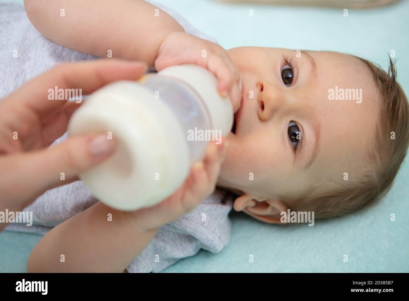 il bambino beve il latte da un biberon Foto Stock