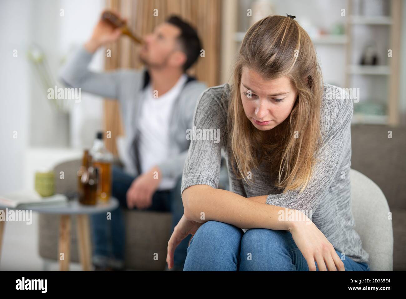 uomo versando alcol e donna seduta turbato Foto Stock
