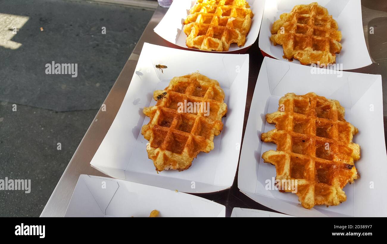 Le api volano e atterrano su waffle belgi all'aperto Un fornitore di cibo di strada a Parigi, Francia Foto Stock