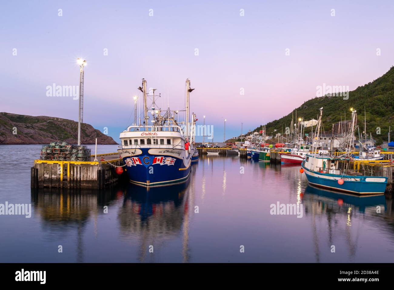 St. John's, Terranova/Canada-Ottobre 2020: Imbarcazioni da pesca di dimensioni multiple, luminose e colorate, in un molo di legno con il cielo rosa della sera. Foto Stock