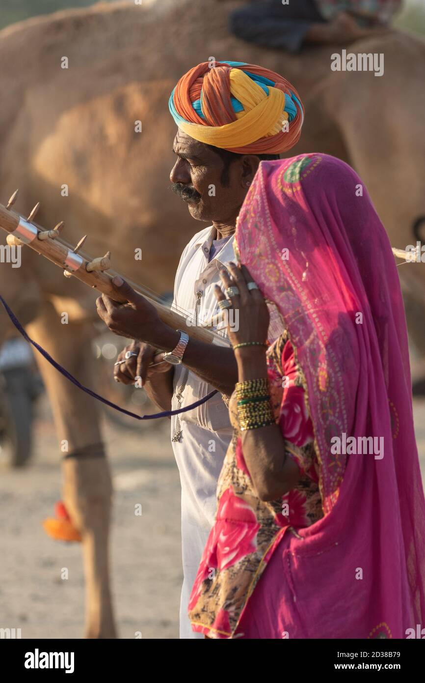 L'uomo e una donna indossano abiti rajasthani suonando violino strumentale al festival Pushkar a Pushkar, Rajasthan, India il 19 novembre 2018 Foto Stock
