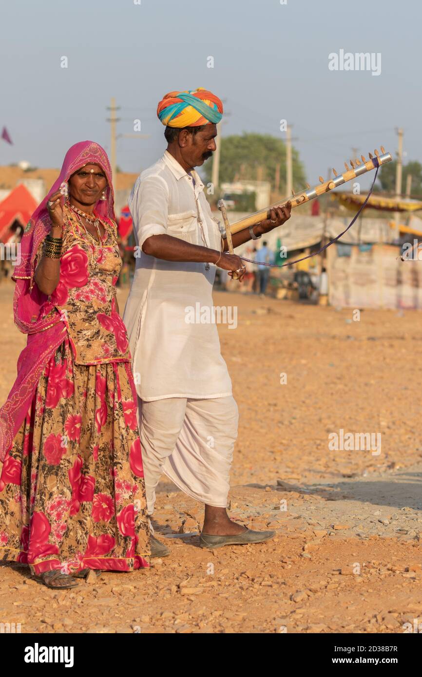 L'uomo e una donna indossano abiti rajasthani suonando violino strumentale al festival Pushkar a Pushkar, Rajasthan, India il 19 novembre 2018 Foto Stock