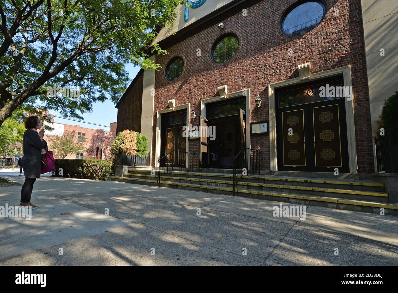 Una donna si ferma a pregare di fronte alla Chiesa cattolica di nostra Signora dell'Angelus nella zona rossa designata di Rego Park, Queens, NY, 7 ottobre 2020. Gov. Andrew Cuomo ha adottato un sistema di zone colorate a tre livelli (giallo, arancione e rosso), piuttosto che utilizzare i codici di avviamento postale, per identificare i quartieri che stanno vedendo un picco significativo nelle infezioni da Coronavirus, e imporre diverse restrizioni in base al colore della zona, il rosso essendo il più alto. Le restrizioni della zona rossa includono un massimo di 10 persone all'interno delle case di culto, sono vietate le riunioni di gruppo, solo le imprese essenziali possono rimanere aperte, Foto Stock