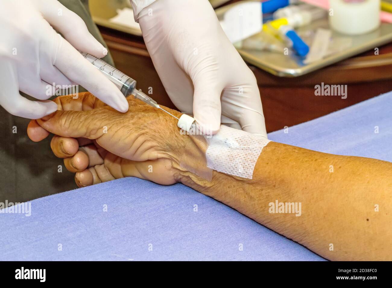 Siringa a pressione del medico nel tappo eparina mano del paziente Foto Stock