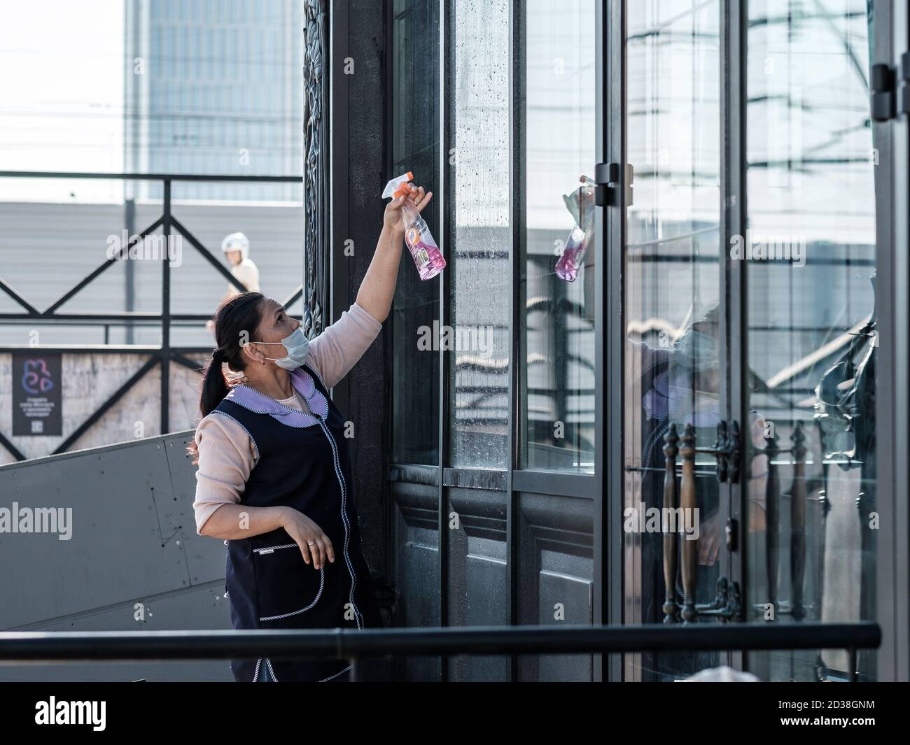 Mosca. Russia. 4 ottobre 2020. Una donna che pulisce il servizio spray detergente sulle grandi finestre anteriori di un edificio in una giornata di sole. Donna dentro Foto Stock