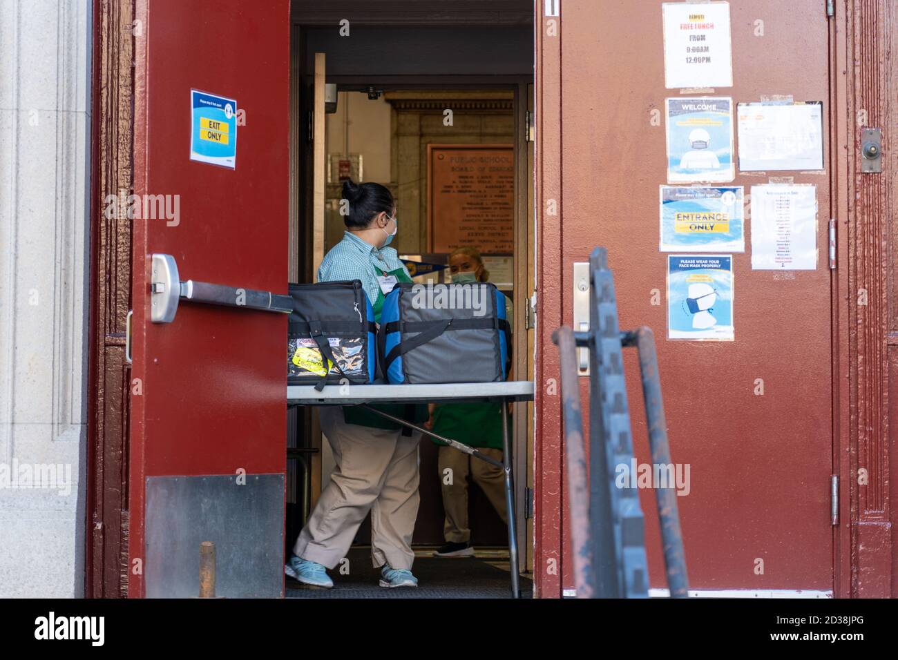 NEW YORK, NY - 07 OTTOBRE 2020: Impiegato scolastico con pranzi scolastici gratuiti per i genitori a prendere per gli studenti al P.S. 231 a Brooklyn. Foto Stock