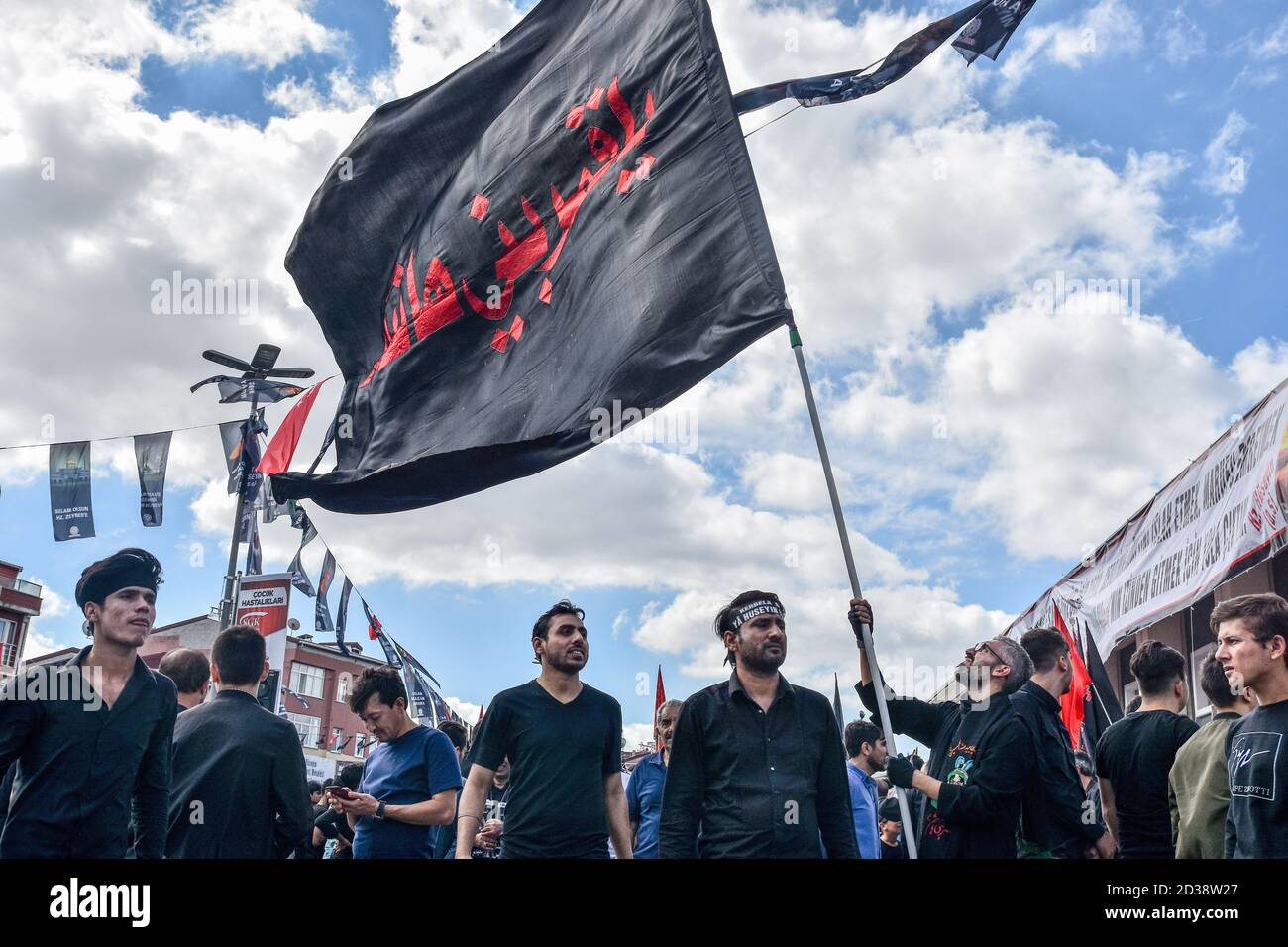 I musulmani sciiti che vivono in Turchia sventolando una bandiera enorme nella piazza ad anello durante la processione di Ashura. Ashura è una delle feste più importanti per i musulmani sciiti e un periodo di lutto per l'assassinio del nipote del profeta Maometto Imam Hussein nel settimo secolo è il decimo giorno del mese di Muharram. Foto Stock