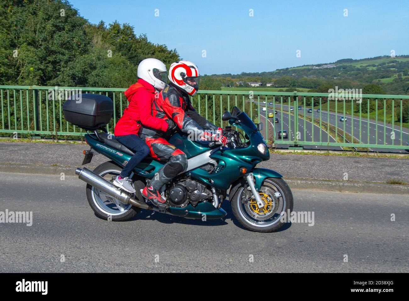 Passeggero di Pillion femmina che tiene stretto su 2005 Triumph Sprint RS motociclista verde; due ruote di trasporto, moto, veicolo, strade, moto, motociclisti che guidano a Chorley, Regno Unito Foto Stock