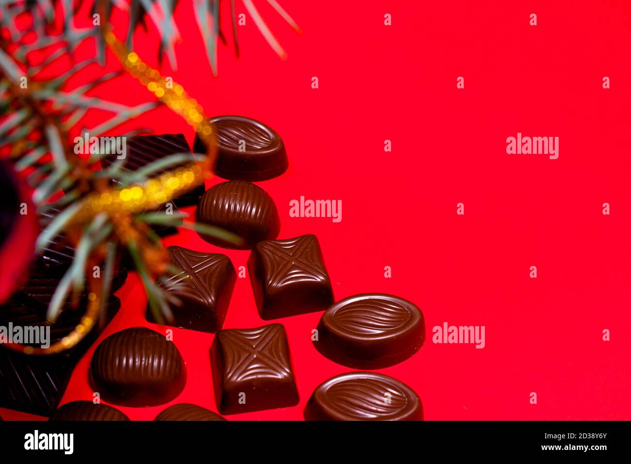 Cioccolatini su sfondo rosso con spazio per il testo. Decorazione e cioccolato di Capodanno - foto festiva per pasticceria. Foto Stock