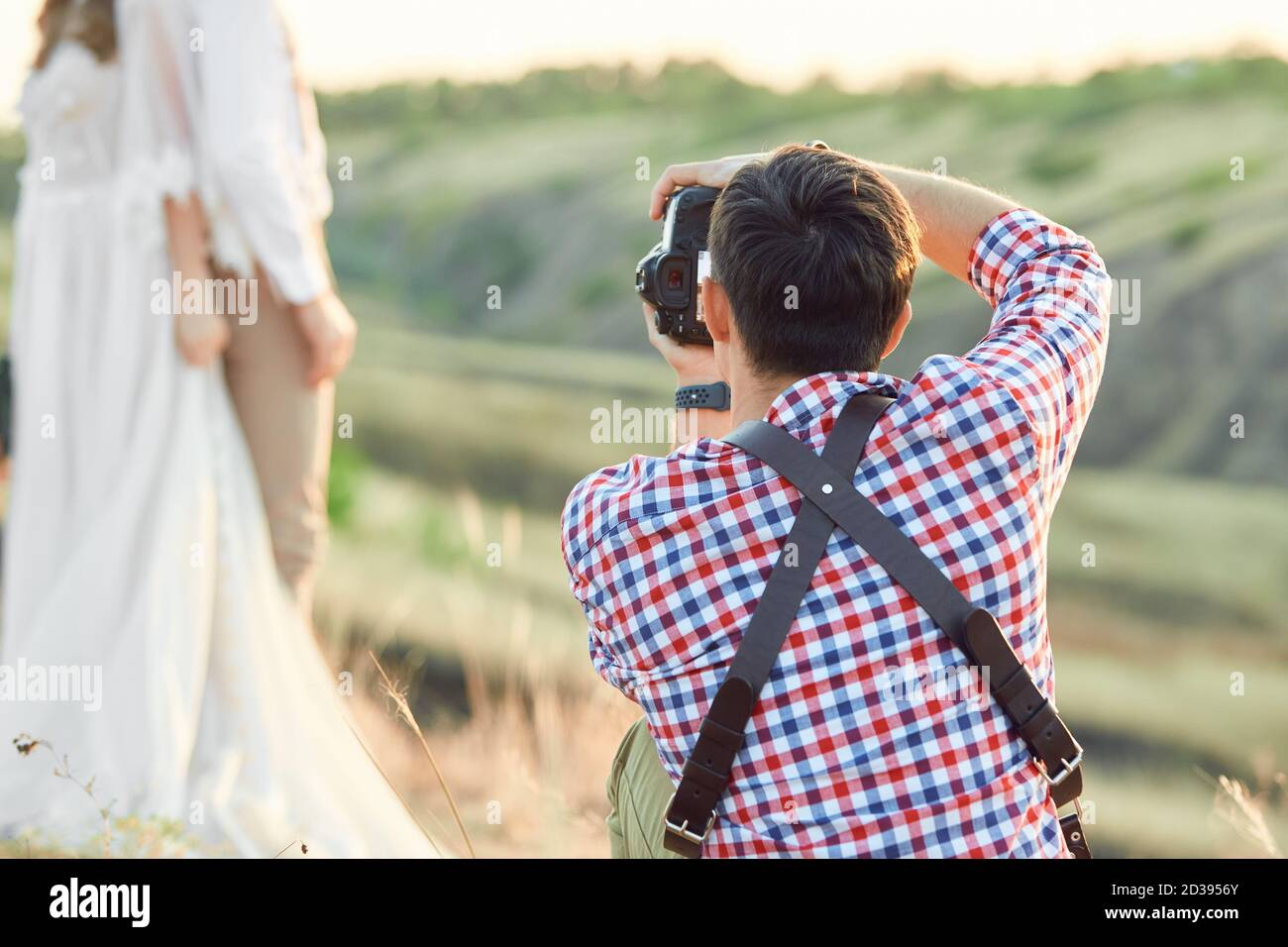 fotografo professionista di matrimoni scatta foto dello sposo e dello sposo in natura al tramonto, fotografo uomo in azione Foto Stock