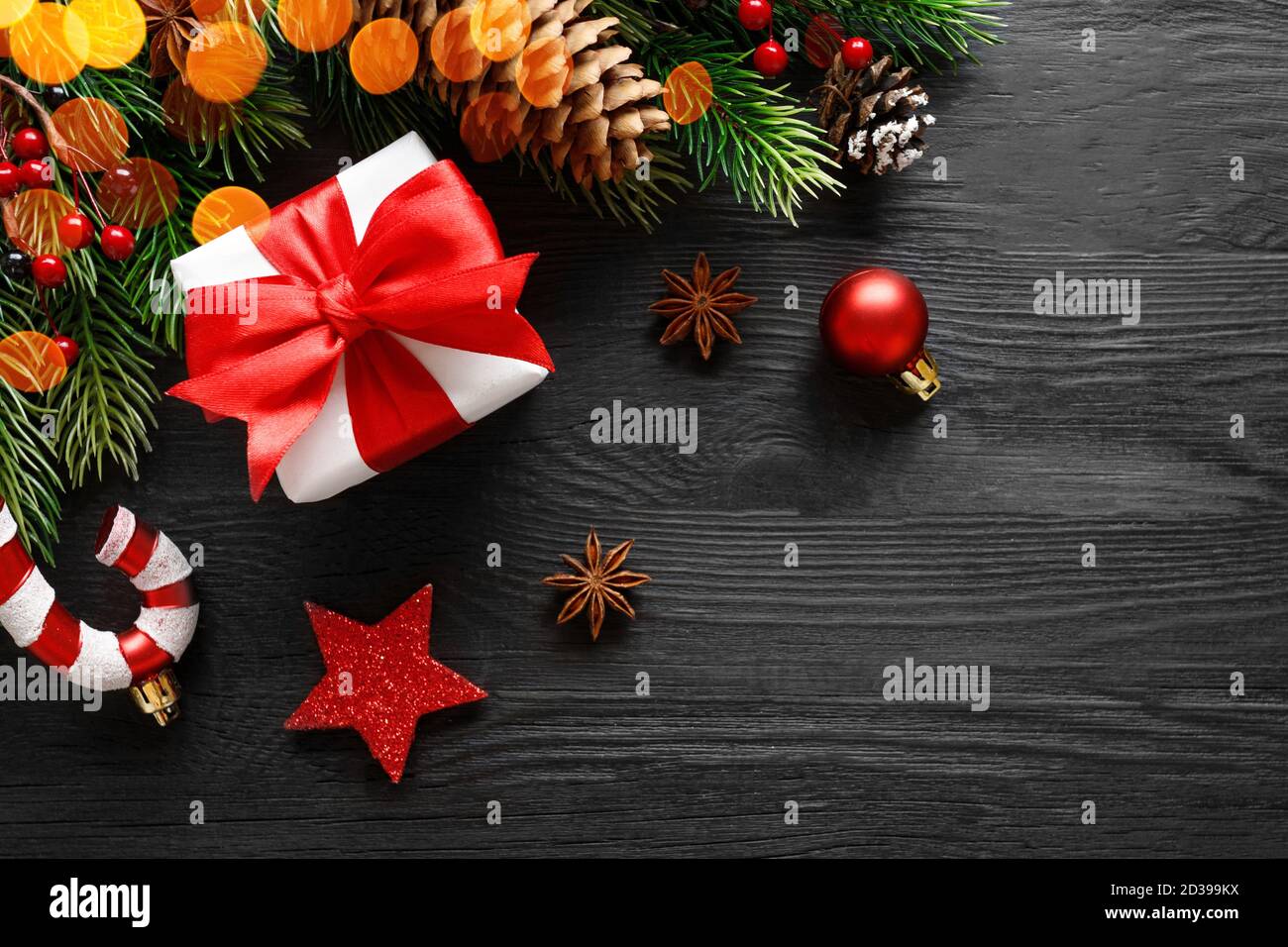 Confezione regalo di Natale con arco rosso e decorazioni su nero sfondo di legno Foto Stock