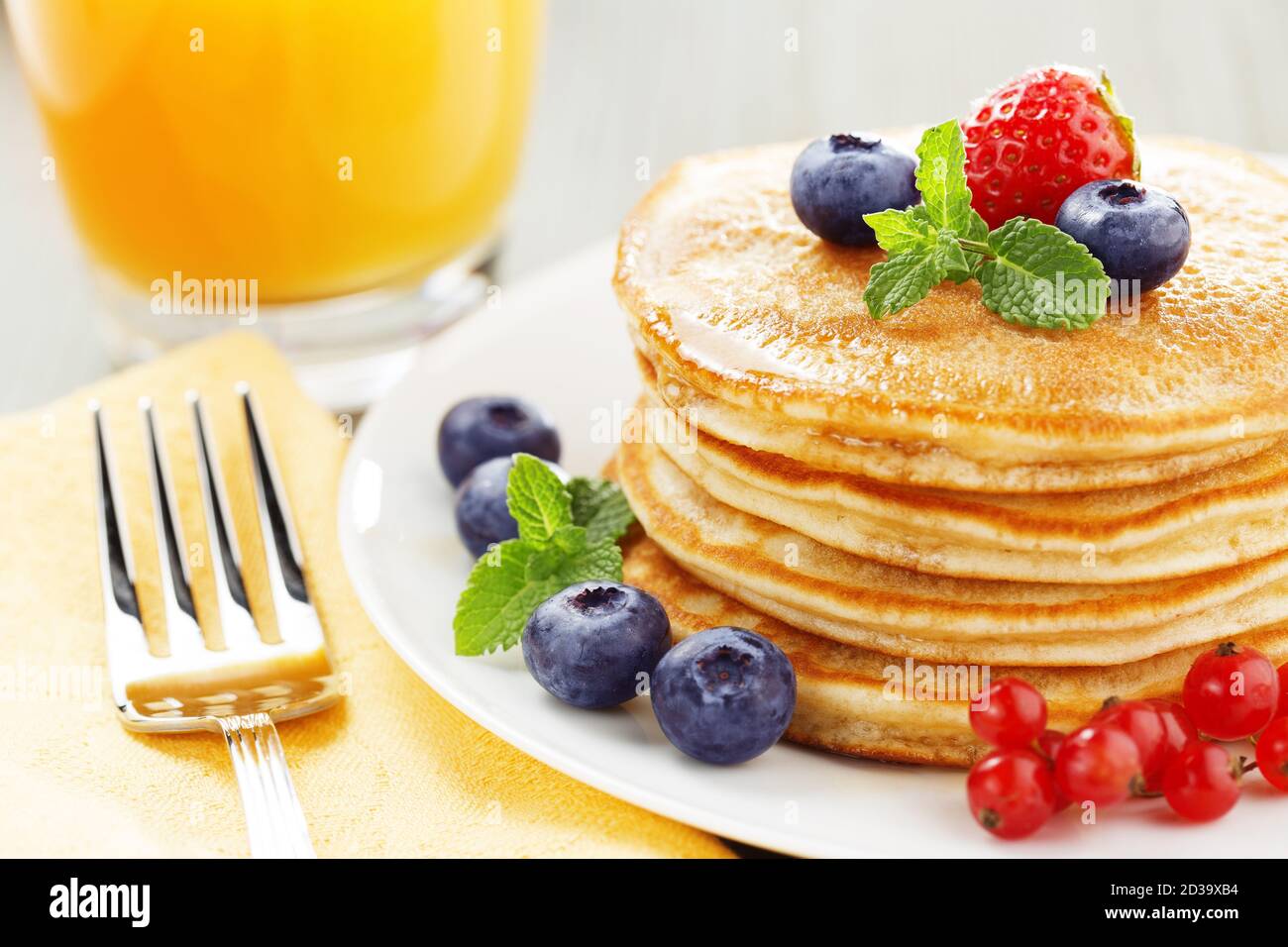 pila di frittelle con frutti di bosco e succo d'arancia Foto Stock