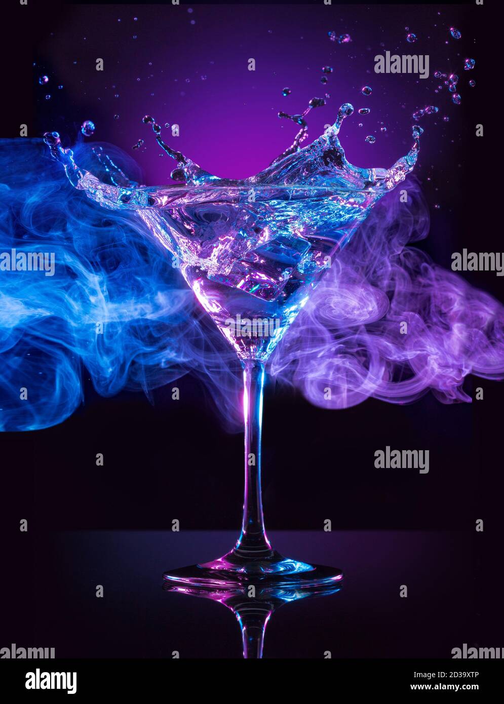 cocktail martini con spruzzi su sfondo blu e viola fumoso Foto Stock