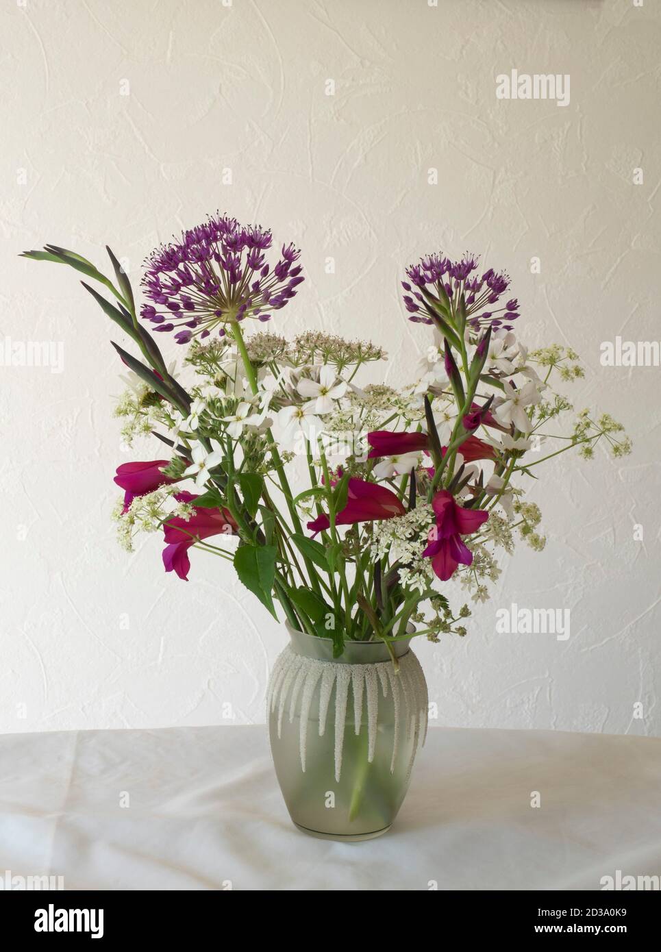 Composizione floreale in vaso di vetro a motivi geometrici, tra cui Allium, Gladiolo bizantino e la zizzania vescovile comune o il pizzo della regina Anna. Foto Stock