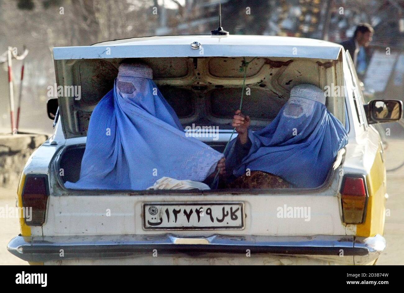 Le donne afghane velate cavalcano nel bagagliaio di un'auto a Charikar, a  nord di Kabul, il 18 febbraio 2003. Il burqa, che avvolge una donna dalla  testa ai piedi, è diventato un
