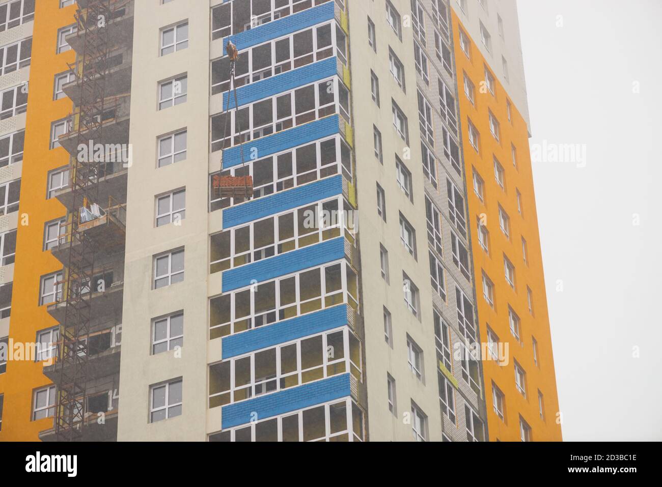 Concetto di edificio di appartamenti in costruzione da vicino. Esterno di un nuovo edificio residenziale multicolore a più piani. Sfondo con pareti gialle, Foto Stock