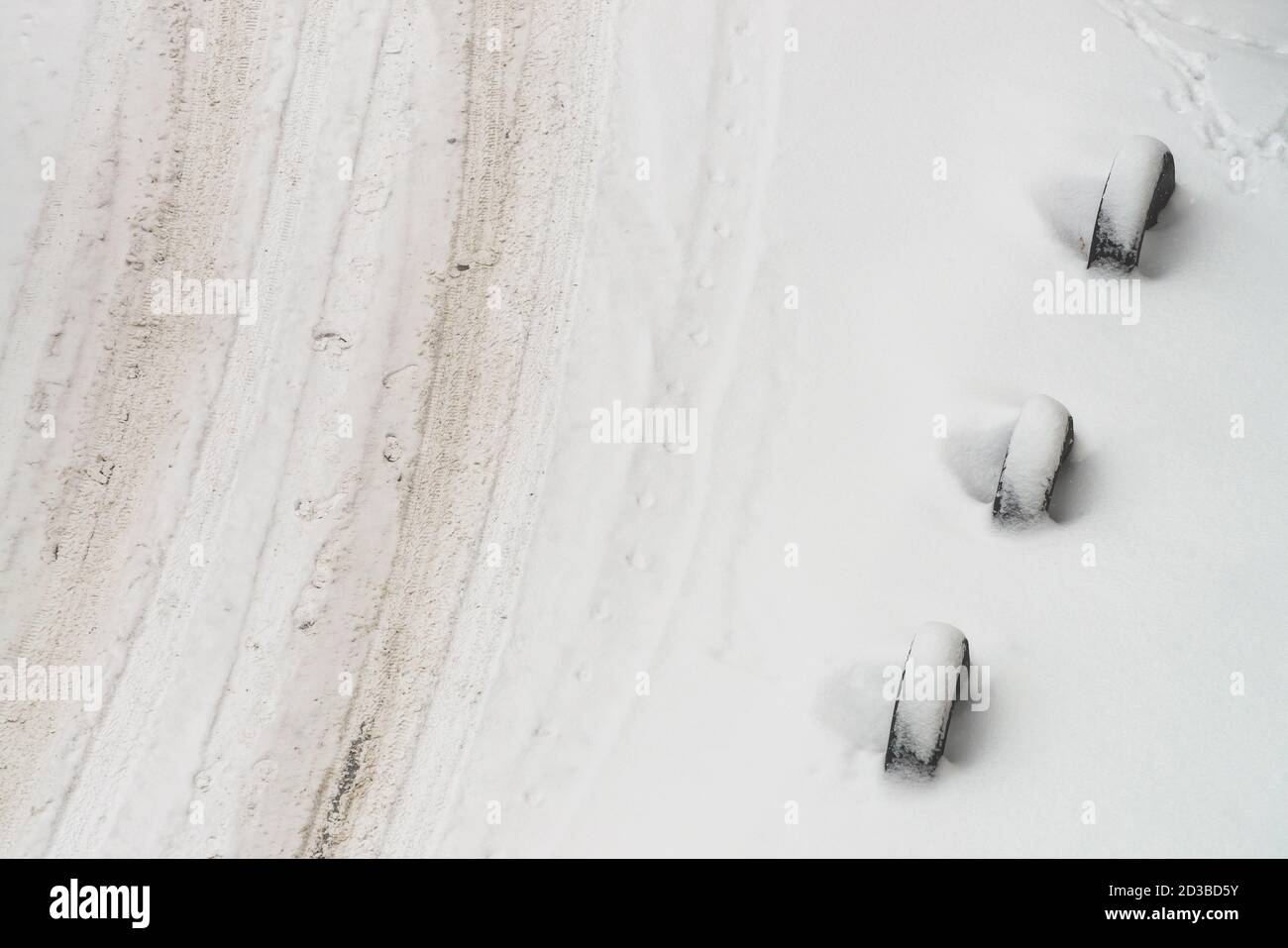 Strada innevata. Recinzione di vecchie ruote. Recinzione dagli pneumatici. Sfondo invernale testurizzato. Struttura minimalista astratta e nevosa. Pista dell'auto nella neve sporca. V Foto Stock
