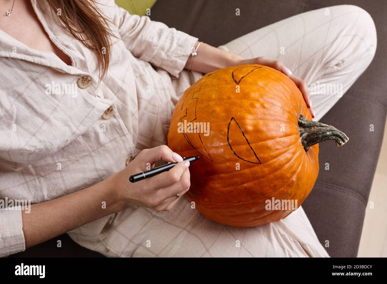 Donna pittura faccia di zucca e facendo lanterna jack per Halloween Foto Stock