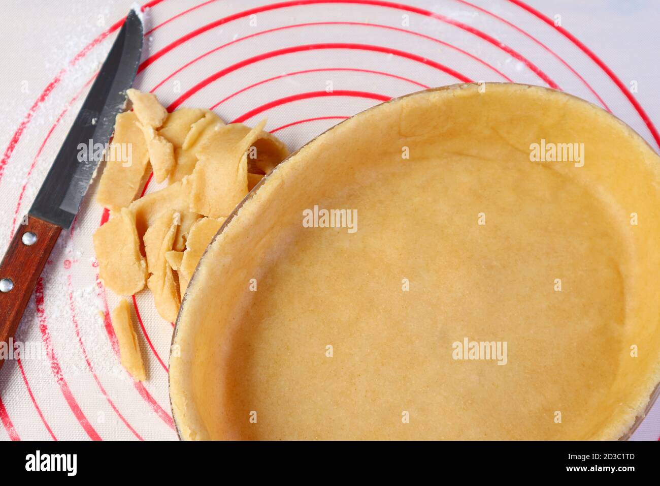 L'impasto in eccesso è stato tagliato via dal recipiente da forno prima di cuocere crosta di torta fatta in casa Foto Stock