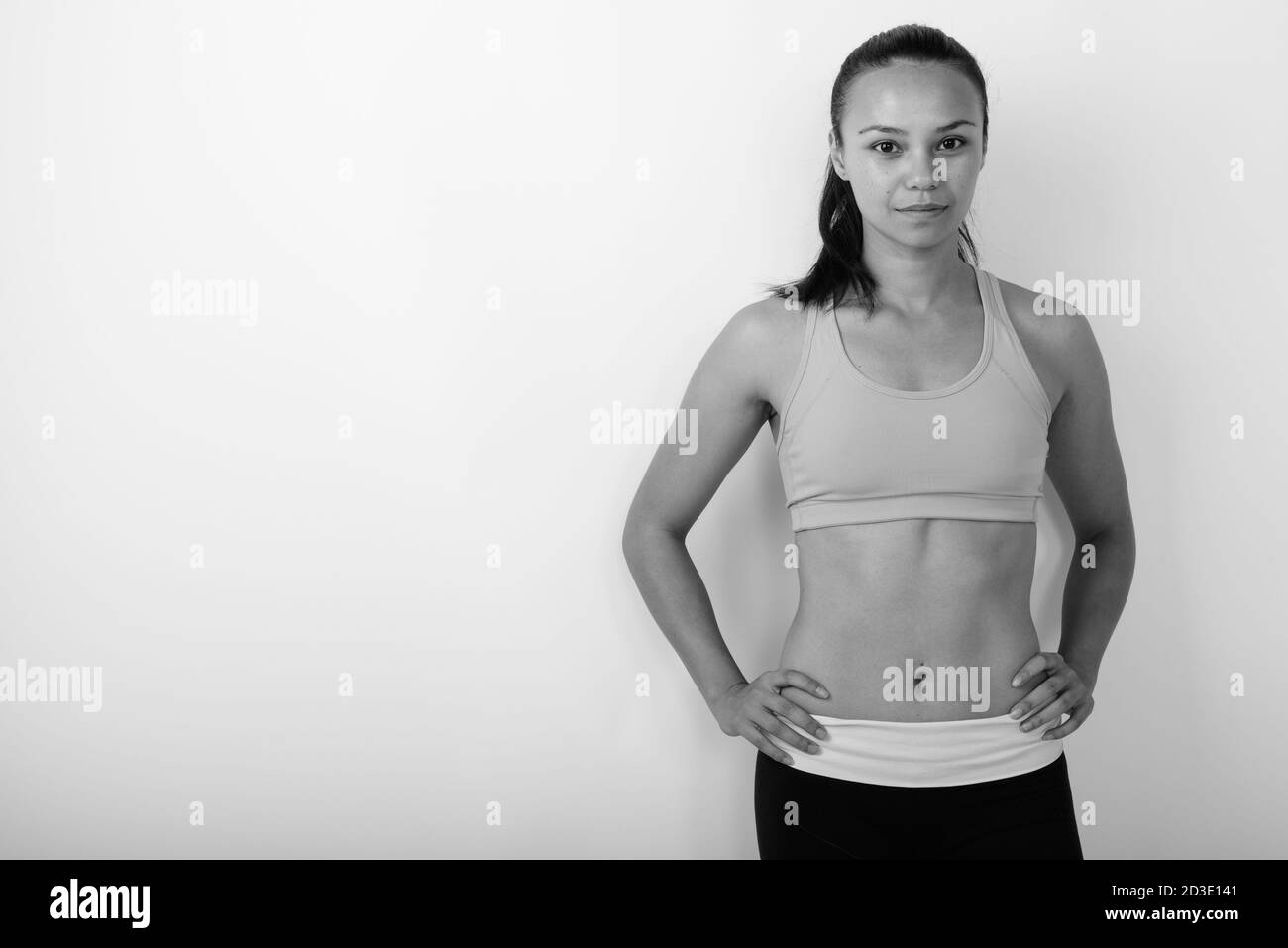 Studio di giovane donna asiatica con mani sui fianchi pronto per la palestra su sfondo bianco Foto Stock