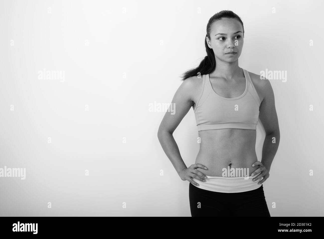 Studio shot di giovane donna asiatica che pensa mentre posa e. pronto per la palestra su sfondo bianco Foto Stock
