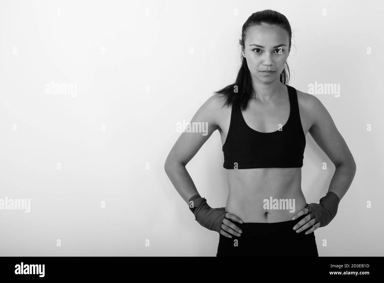 Studio di giovane donna asiatica combattente in posa con le mani su fianchi su sfondo bianco Foto Stock