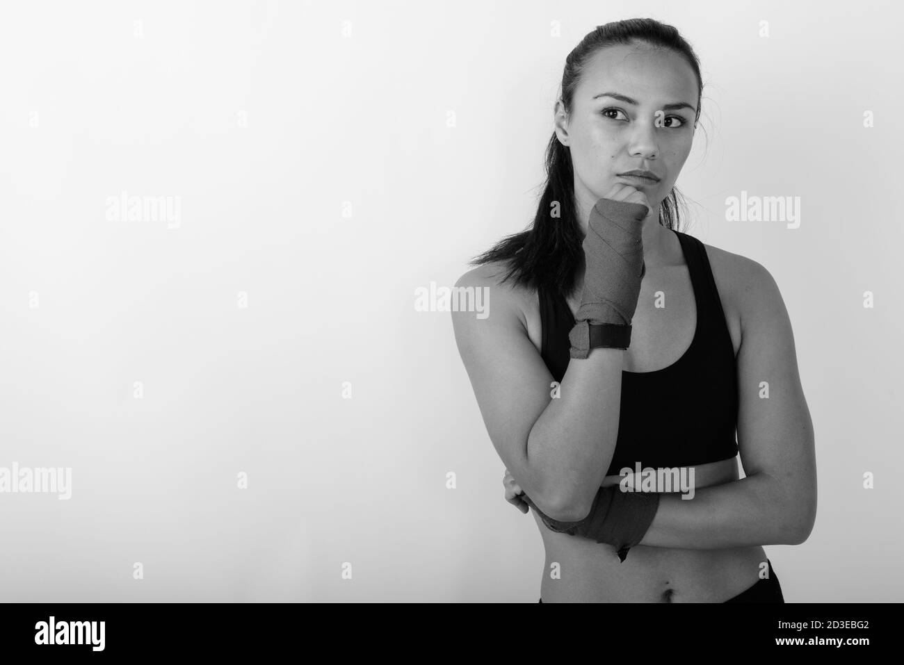 Studio girato di giovane donna asiatica combattente pensare e guardare a distanza con involucri di boxe Foto Stock