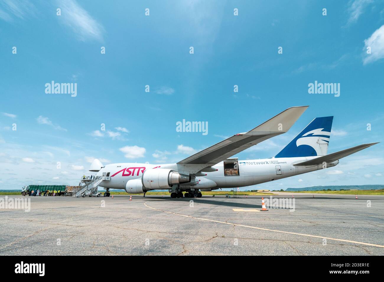 Vista panoramica di un aeromobile Boeing 747 Jumbo Jet Freighter con una porta vano di carico a naso largo aperto scaricata da un caricatore alto su una rampa di carico Foto Stock