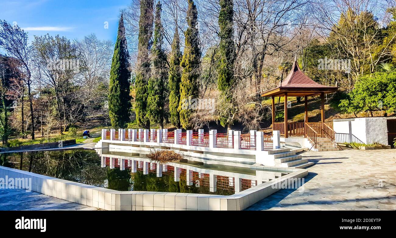 Gazebo in legno e laghetto incorniciato da pietra bianca nell'arboreto di Sochi. Russia Foto Stock