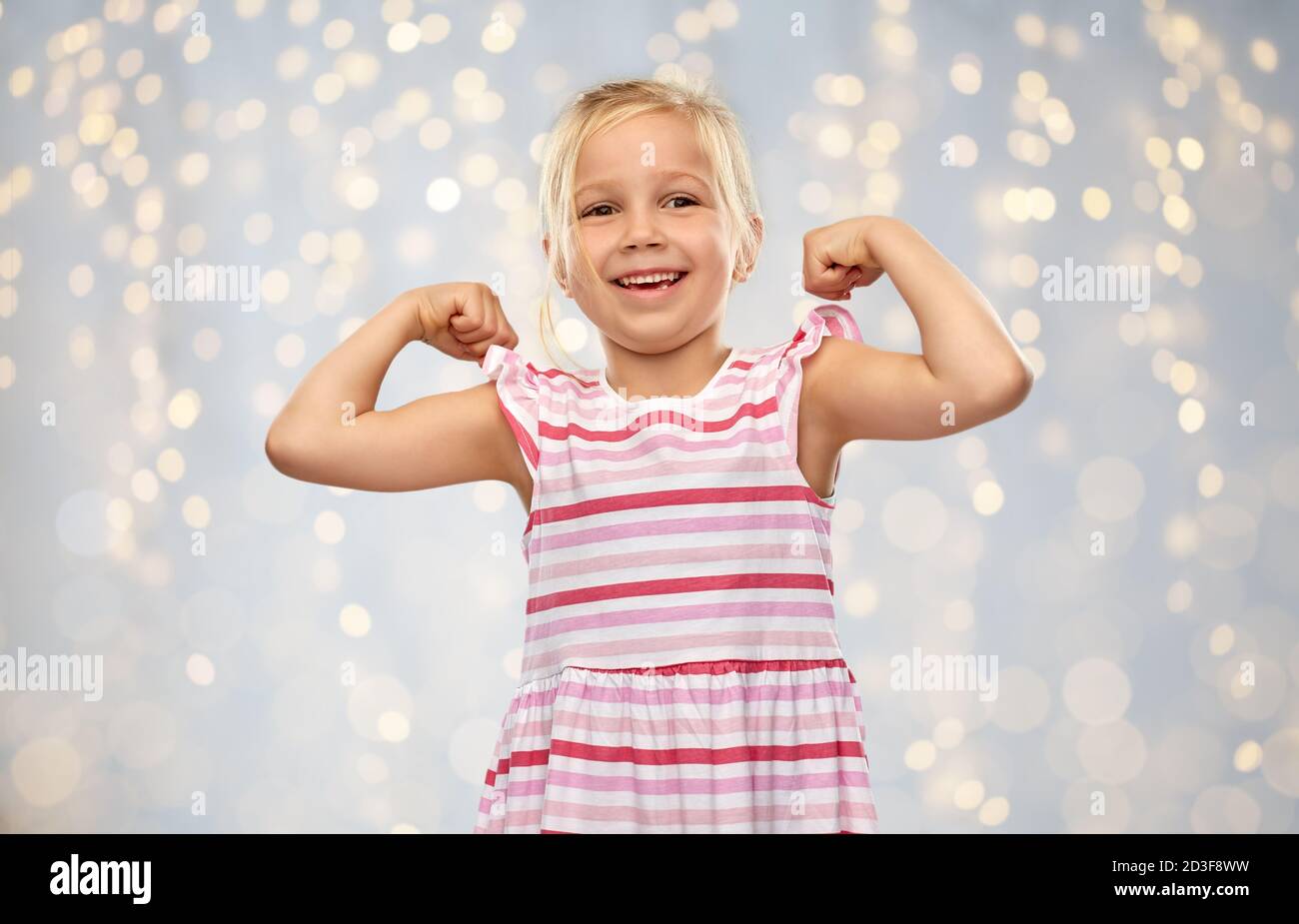 sorridente bambina che mostra il suo potere Foto Stock