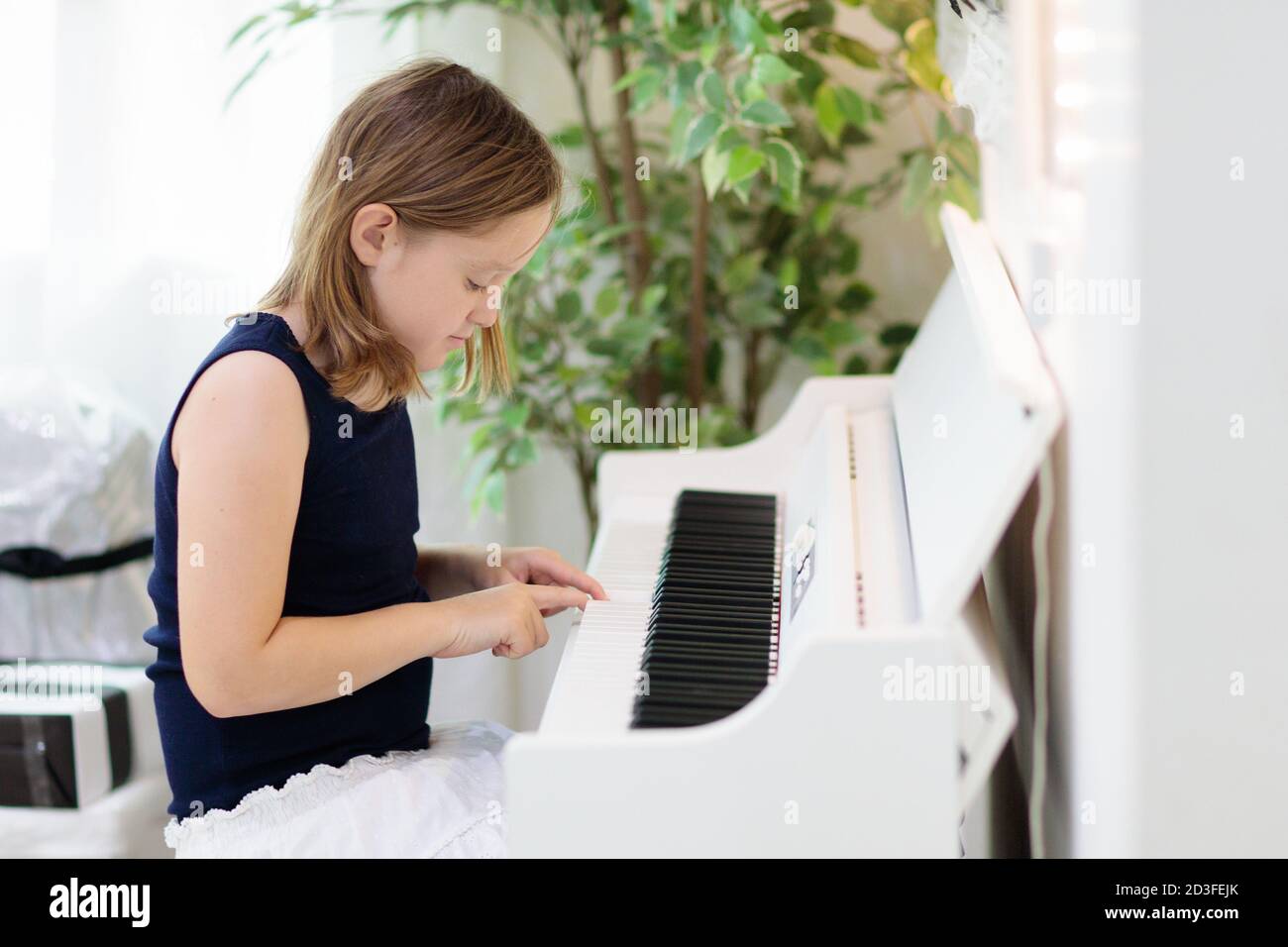 Bambino che suona piano. I bambini giocano la musica. Pianoforte digitale  bianco per lezioni per bambini.
